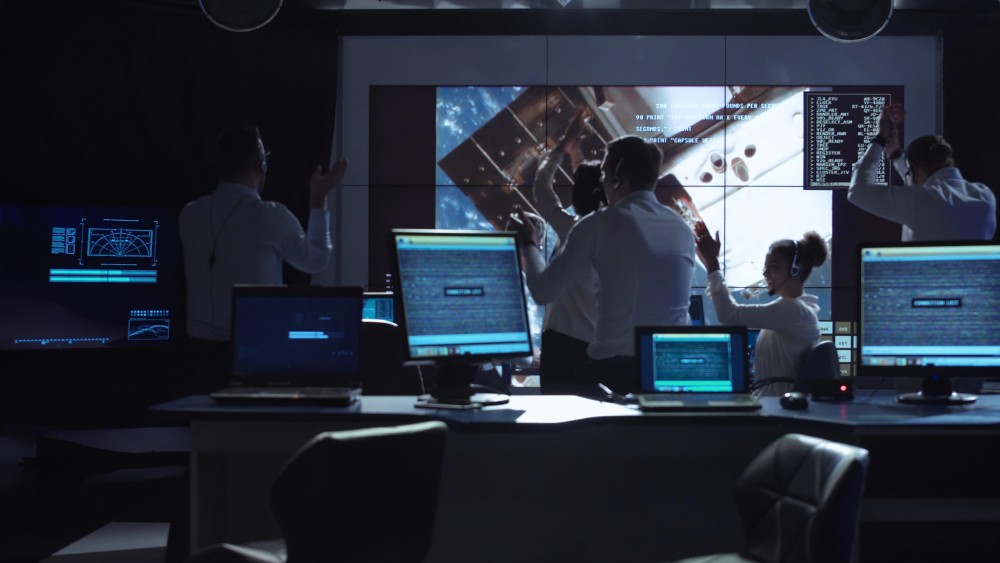 Group of supervisors celebrating docking of spaceship in dark room of mission control center. Elements of this image furnished by NASA.