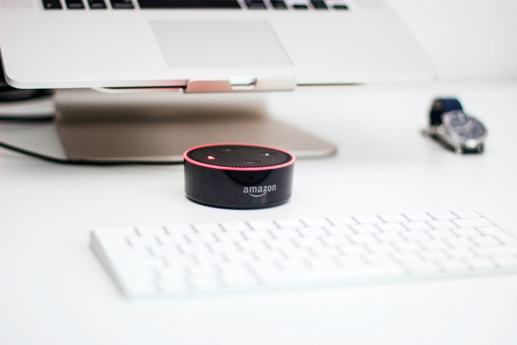 Alexa by Amazon on a desk next to a computer