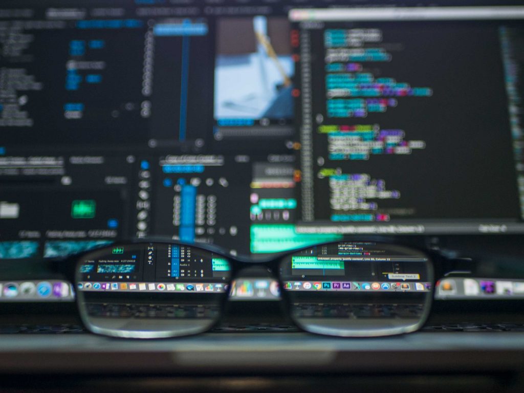 Glasses in front of computer screens with data and codes