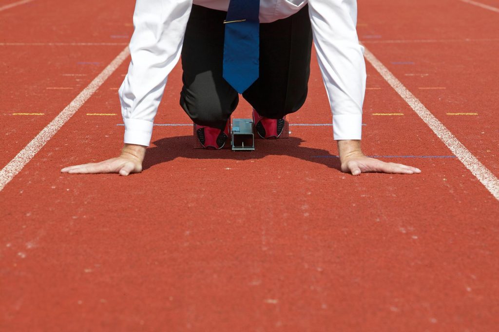 Businessman in a starting block on a stadium